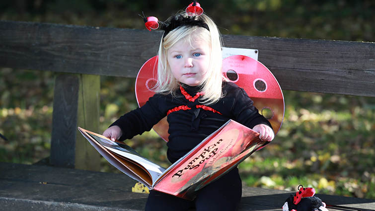 Two-year-old Jess in her Hallowe'en outfit and with a spooky storybook.