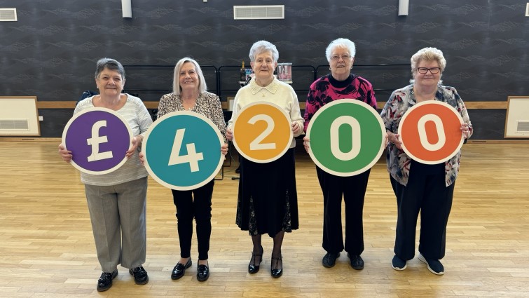This image shows members of Fernhill Communities Together holding up numbers to show the £4200 they were awarded through Participatory budgeting money 