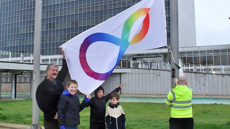 This image shows the autism pride flag being raised in celebration of Autism Awareness week 