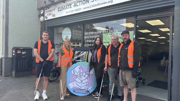 Climate Action Strathaven volunteers outside their office, holding new litter-pickers donated by RACAM through the Community Wish List.