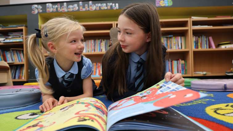 two pupils enjoying reading a book together