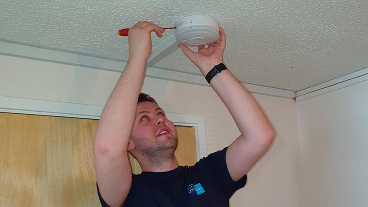 This image shows a council worker fixing a smoke alarm 