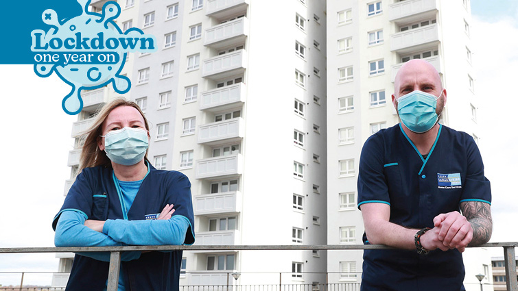 this pic shows two SLC Home Carers with face masks on and high-rise flats in Cambuslang in the background