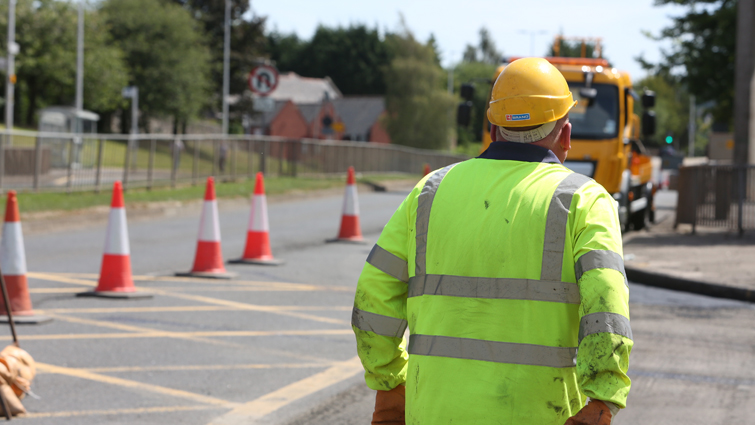 A roads worker at a road coned off for improvements 