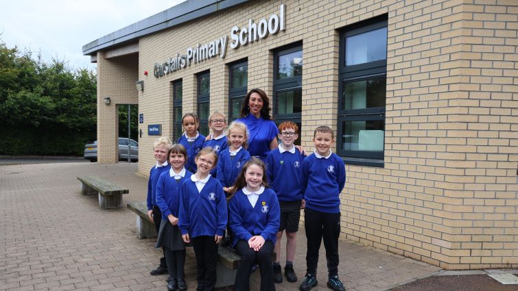 Head Teacher Angela Sneddon is pictured with a small group of pupils in uniform, outside the school.