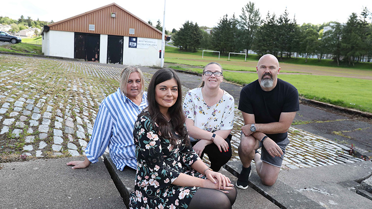 Sian Flynn from the community engagement team sits with three members of the Friends of Westwoodhill group in front of the local sports pavilion.