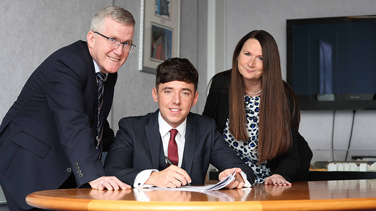 In this photograph from left to right is South Lanarkshire Council (SLC) Executive Director of Housing and Technical Resources Daniel Lowe, Chair of Housing Councillor Josh Wilson who is seated at a desk and Head of Housing Annette Finnan