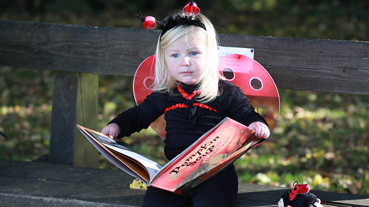 Two-year-old Jess in her Hallowe'en outfit and with a spooky storybook. 