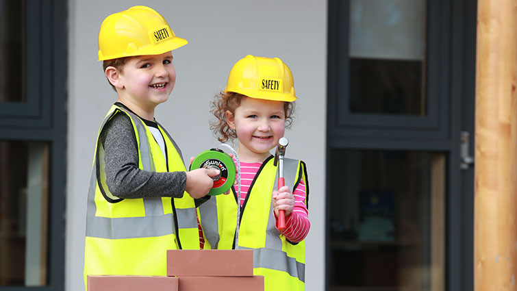 This photo shows two young nursery children with construction tools and equipment to help publicise upcoming Jobs Fairs