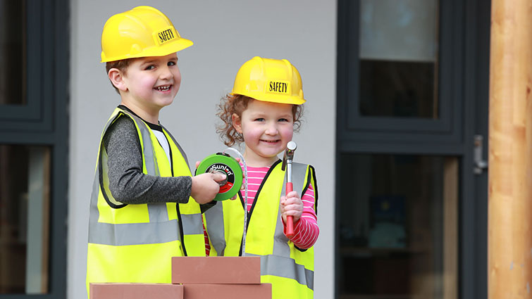 This photo shows two young nursery children with construction tools and equipment to help publicise upcoming Jobs Fairs 