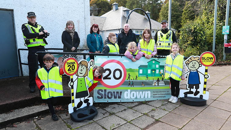 This image shows a variety of people outside Kirkfieldbank Primary School to reinforce the message that mandatory 20mph limits are now in force