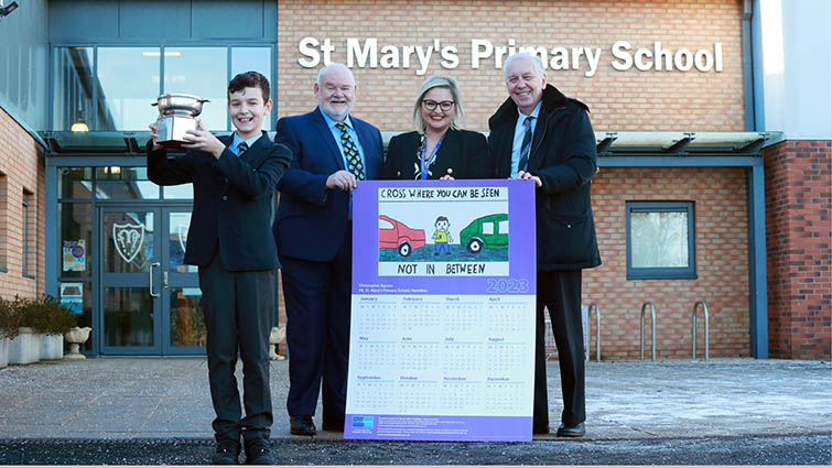 This image shows the winner of the council's annual road safety calendar competition with Councillors Davie McLachlan and Robert Brown and the school's deputy head teacher