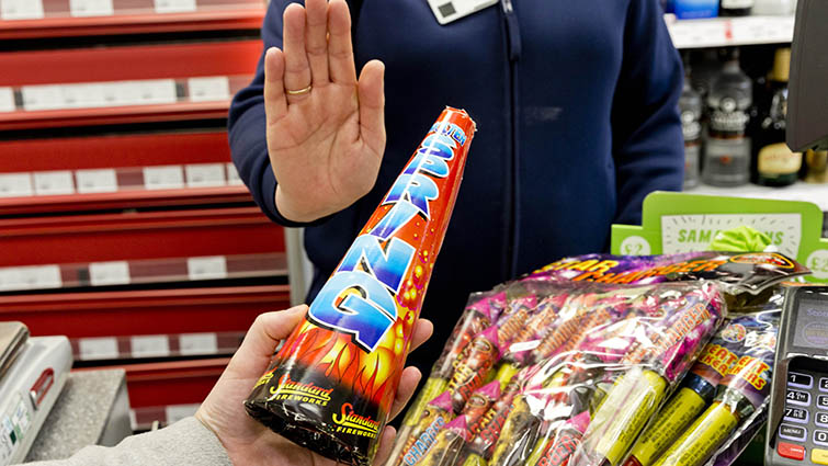 A local shop worker refuses to sell fireworks when approached at the till point by a teenager holding the explosives. 