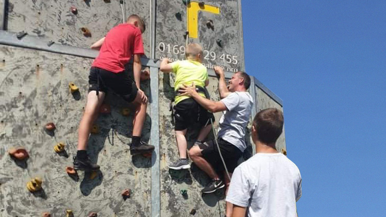 This image shows young people using a climbing wall as part of the sensational summer sessions 