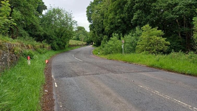 This image shows a section of the A72 which is to undergo improvement works. The image shows a stretch of road with grass at either side and trees in the background