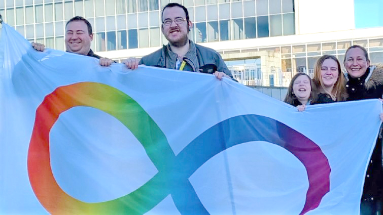Members of the autistic community in South Lanarkshire with the Infinity flag that was flown for Autism Acceptance Week, 2023.