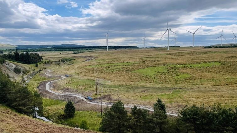This is a scenic image of the Douglas Valley, showing the path between Coalburn and Douglas in the foreground with hills, trees and wind turbines also in the image
