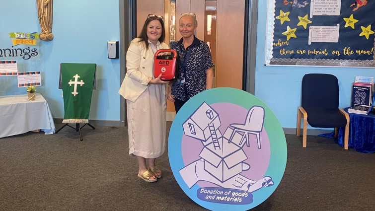 This image shows a member of St Mary's Primary school staff with a representative from Findel after the company donated a defibrillator to the school following a request to the wish list 