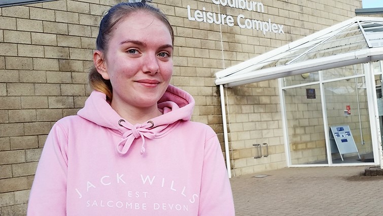 A woman in a pink hooded top stands in front of Coalburn Leisure Complex 