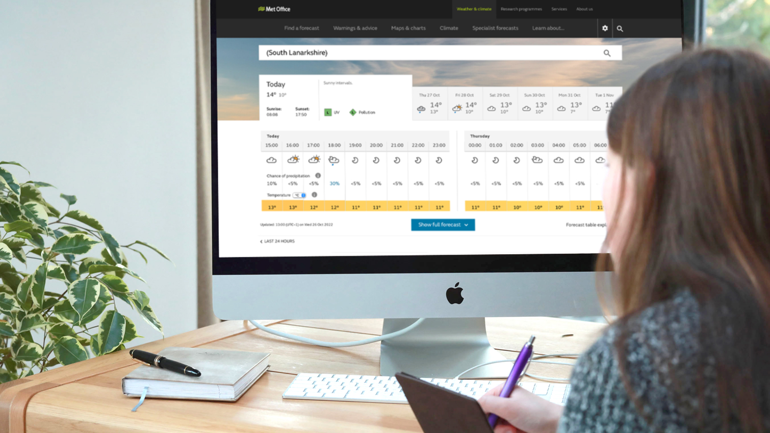 This image shows the back of a person looking at the Met Office website on a computer monitor