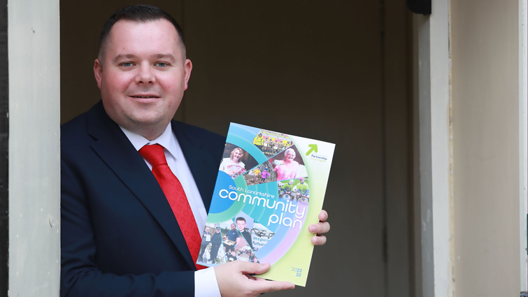 This image shows council leader Joe Fagan with a copy of the new Community Plan for South Lanarkshire 2022-2032 