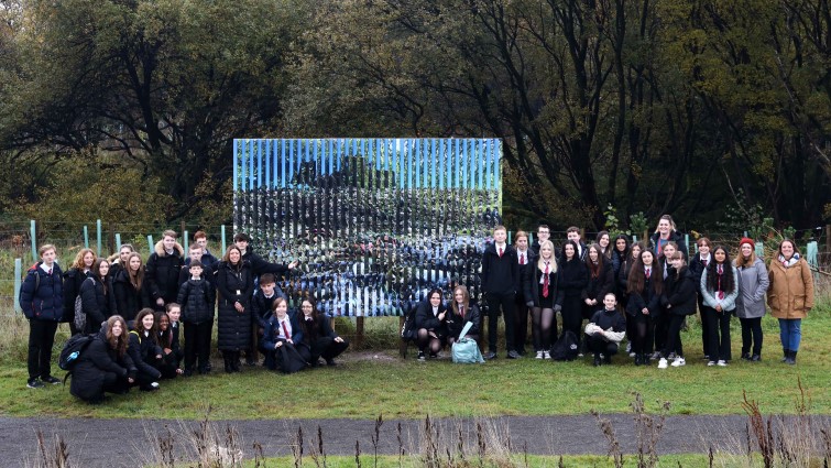 This image shows pupils and staff from Stonelaw High School along with an example of the public artwork created for display at Cuningar Loop