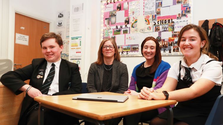 This image shows staff and pupils from Duncanrig Secondary School school with a wall display in the background that shares pupils' achievements, testimonials, experiences and other creative pieces