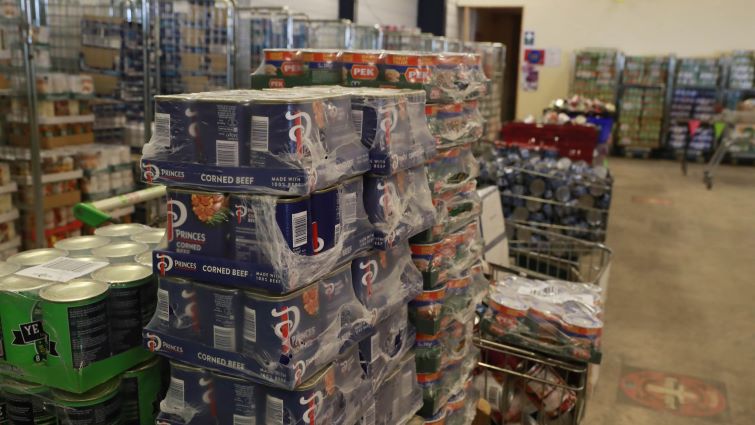 This image shows pallets with various food items in the foreground and background and is to highlight funding from the council to local food banks