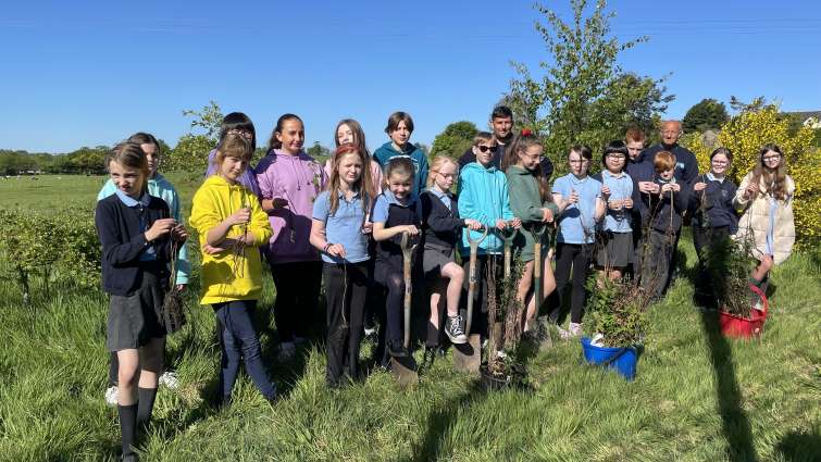 group of primary school pupils getting ready to plant some tree saplings
