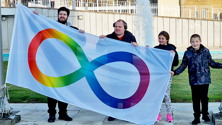 This image shows some members of the South Lanarkshire autism community with the autism infinity flag outside council HQ 