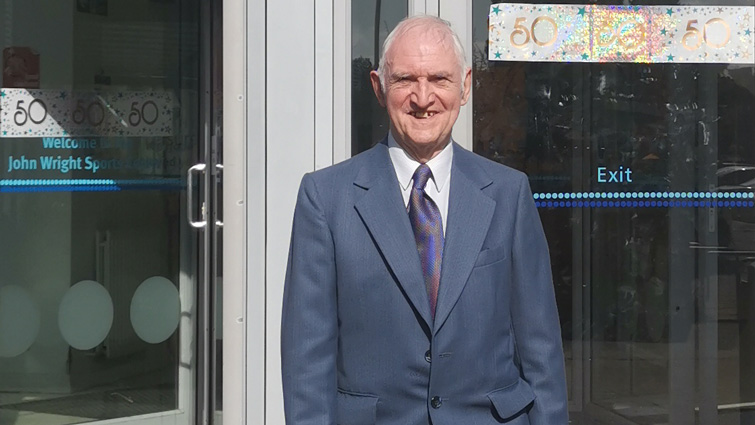 This image shows the son of John Wright outside the John Wright Sports Centre on its 50th anniversary 