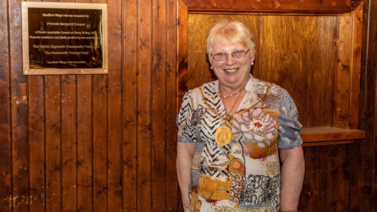 This image shows Provost Margaret Cooper next to a plaque following the reopening of Sandford Village Hall