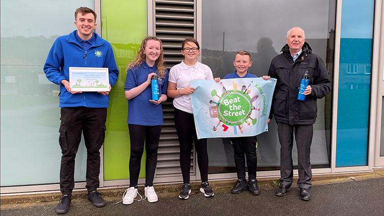 Raymond Hood and Chair of the Community and Enterprise Committee John Anderson hand over a certificate and water bottles to three P7 Spittal  Primary School pupils 