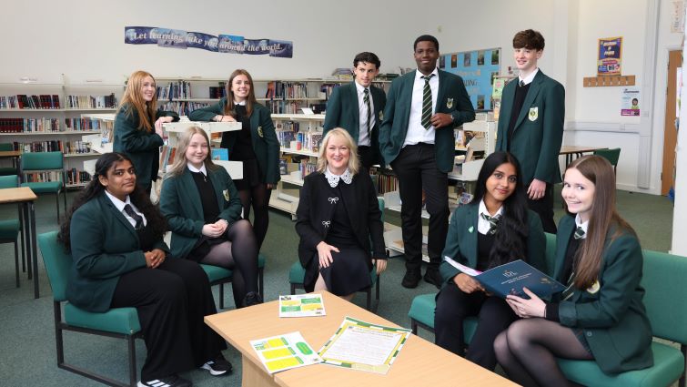 This image shows pupils from St John Ogilvie High School in the library with head teacher Lorna Lawson