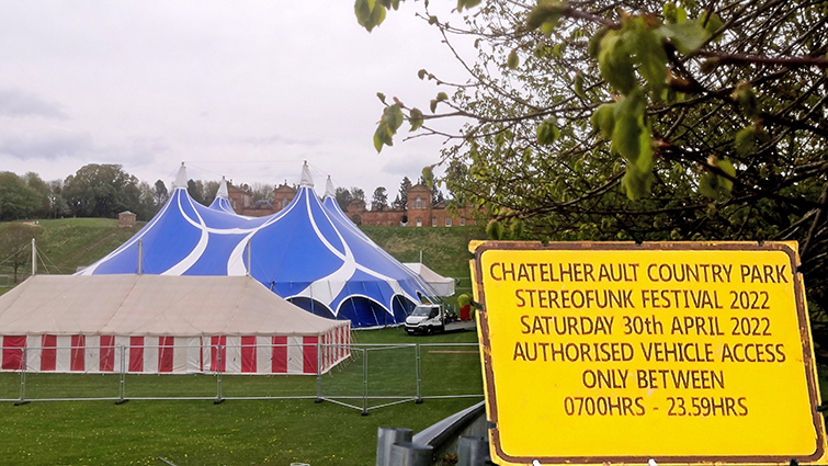 A large marquee, with a circus tent behind it and above and behind them the Hunting lodge at Chatelherault Country Park. A yellow sign advising there will be no vehicle access to Chatelherault during Stereofunk has been superimposed in the foreground.