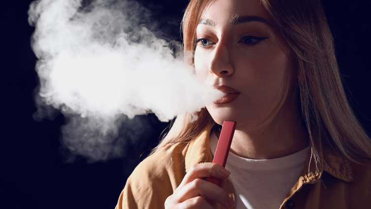 This image shows a young person using a single use vape 