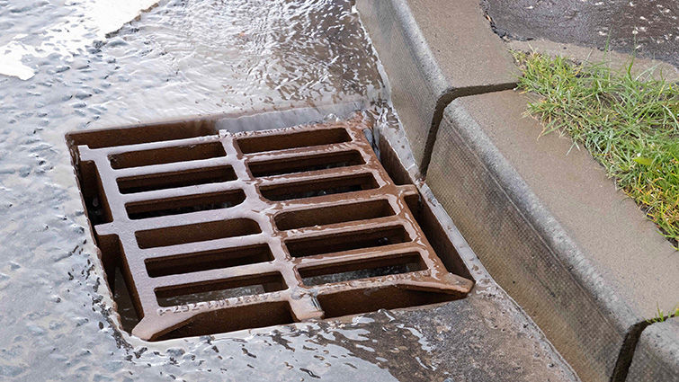 This is an image of a gulley - or drain - in the road with water flowing into it.