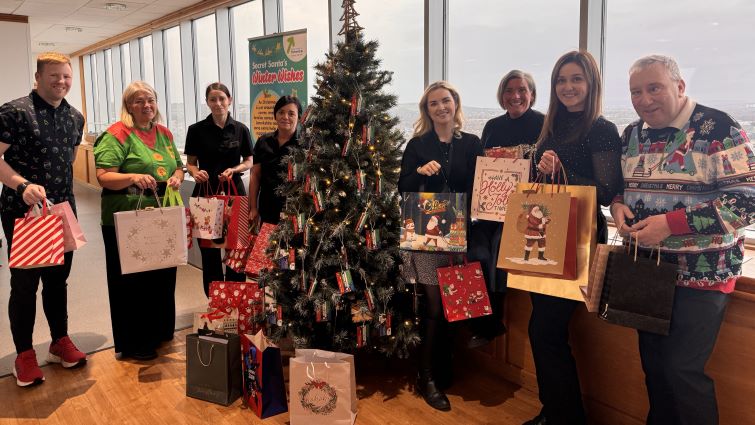 This image shows council staff at a Christmas tree with various gifts donated to help those less fortunate