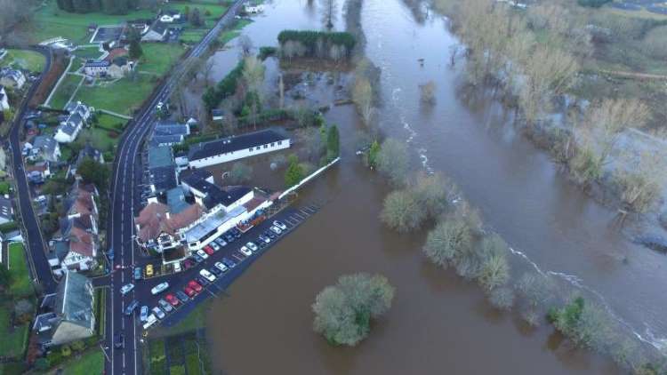 aerial view of a flooded river next to properties