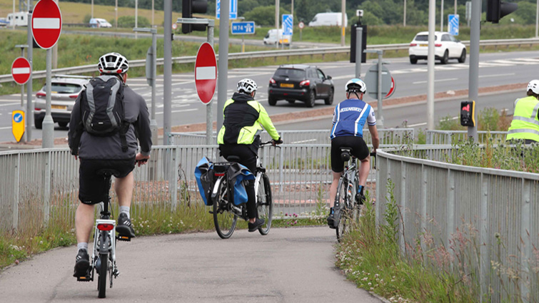 Image shows a group of cyclists on the cycle path at the Raith junction of the M74