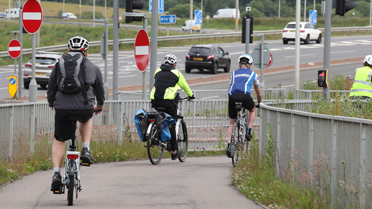 Image shows a group of cyclists on the cycle path at the Raith junction of the M74 