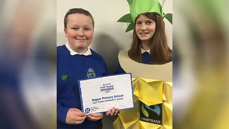 This image shows two pupils from Biggar Primary School after the school were successful in the Scottish Fair Trade awards