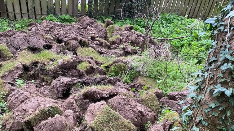 piles of turf dumped over a fence