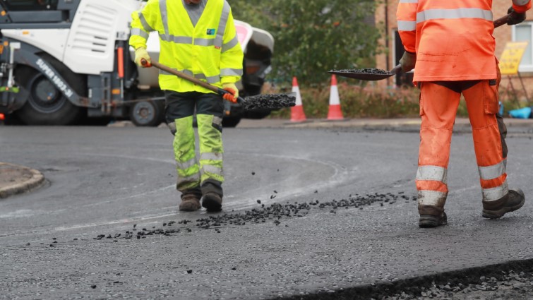 This is a picture showing two roadworkers carrying out resurfacing work on a road in Rutherglen. 