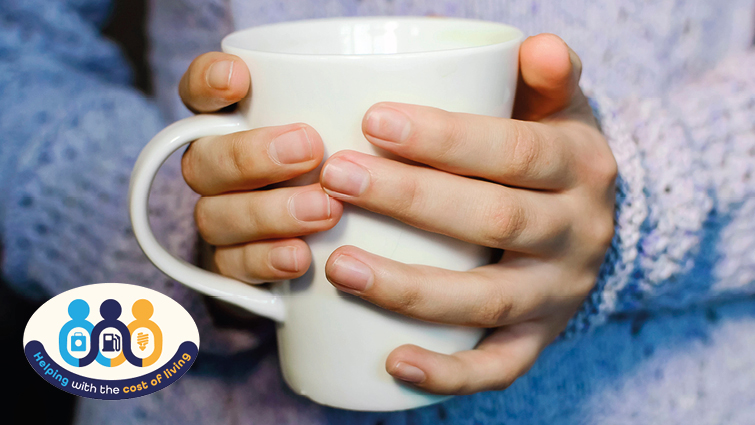 This image shows someone holding a cup of tea and also includes a cost-of-living crisis logo