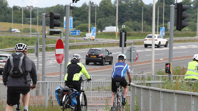 Four cyclists on the new walking and cycling path at the Raith interchange the M74 can be seen in the background.
