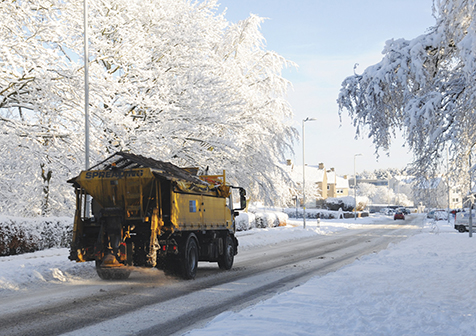 This is a picture of a gritter driving along a snow covered road