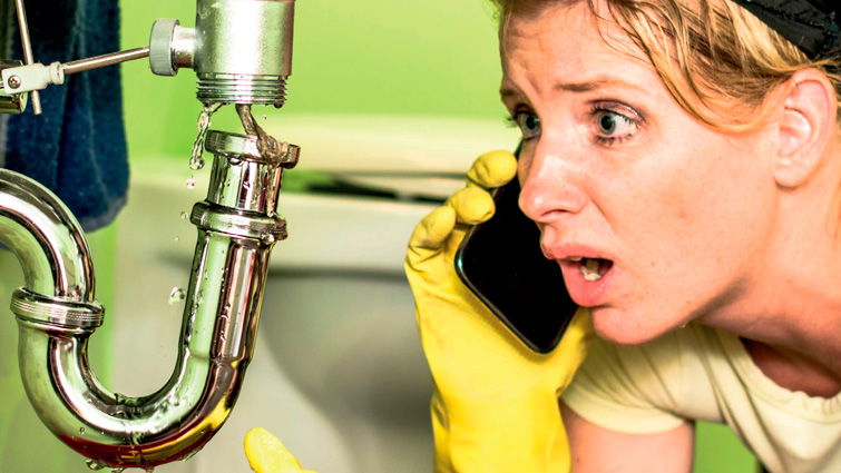 This image shows a woman looking with concern at a burst pipe