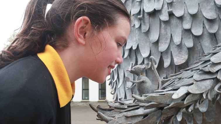 A senior girl from Abington ps, is pictured inspecting the new statue up close, which includes the Gruffalo holding the story's  other central character, the mouse.