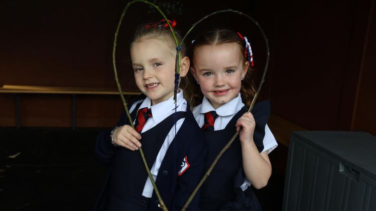 Two young pupils are pictured holding a heart made of twigs from their outside classroom.